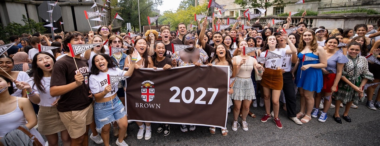 large group of students outside on a sunny day surrounding a banner with class of 2027