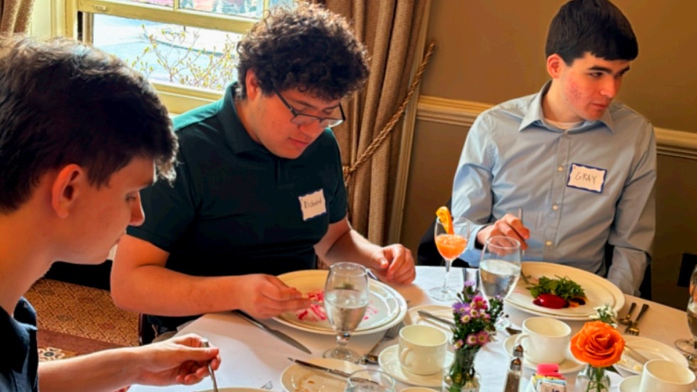 Students sitting at a fine dining table eating dinner