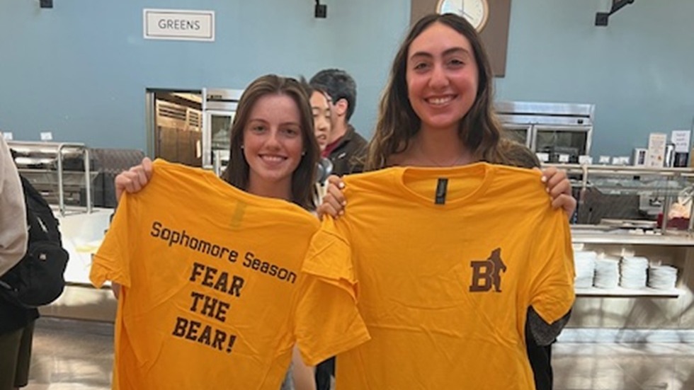 two students holding bright yellow tshirts 
